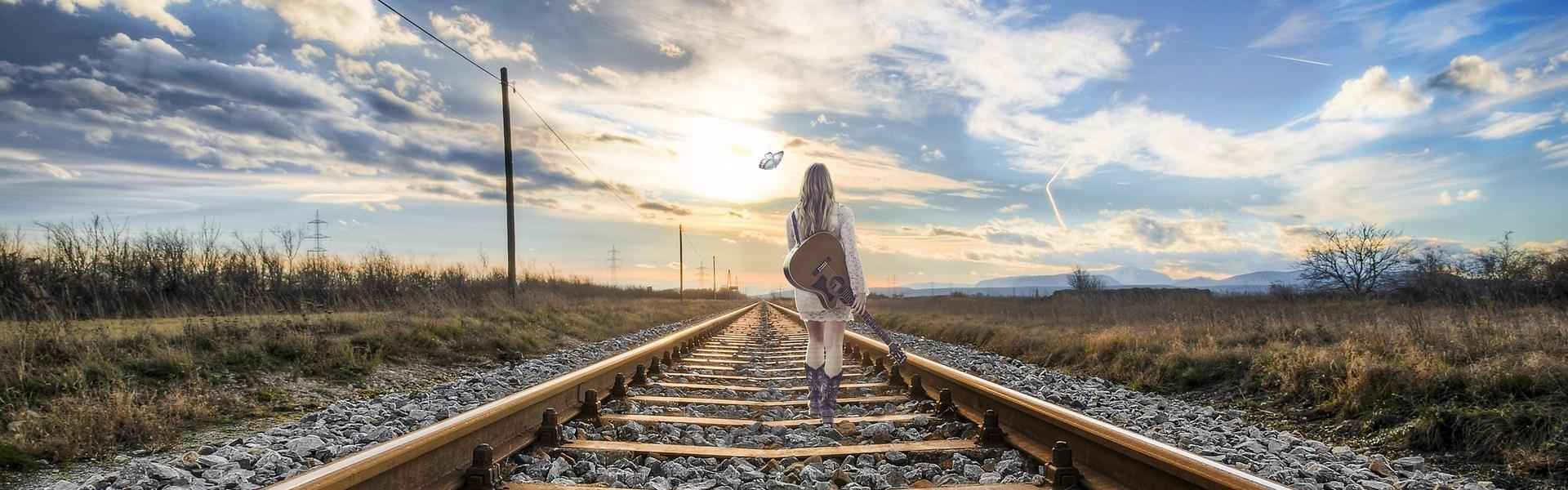 A woman walking alone down a railway track, symbolizing a journey through emotional overwhelm and stress.