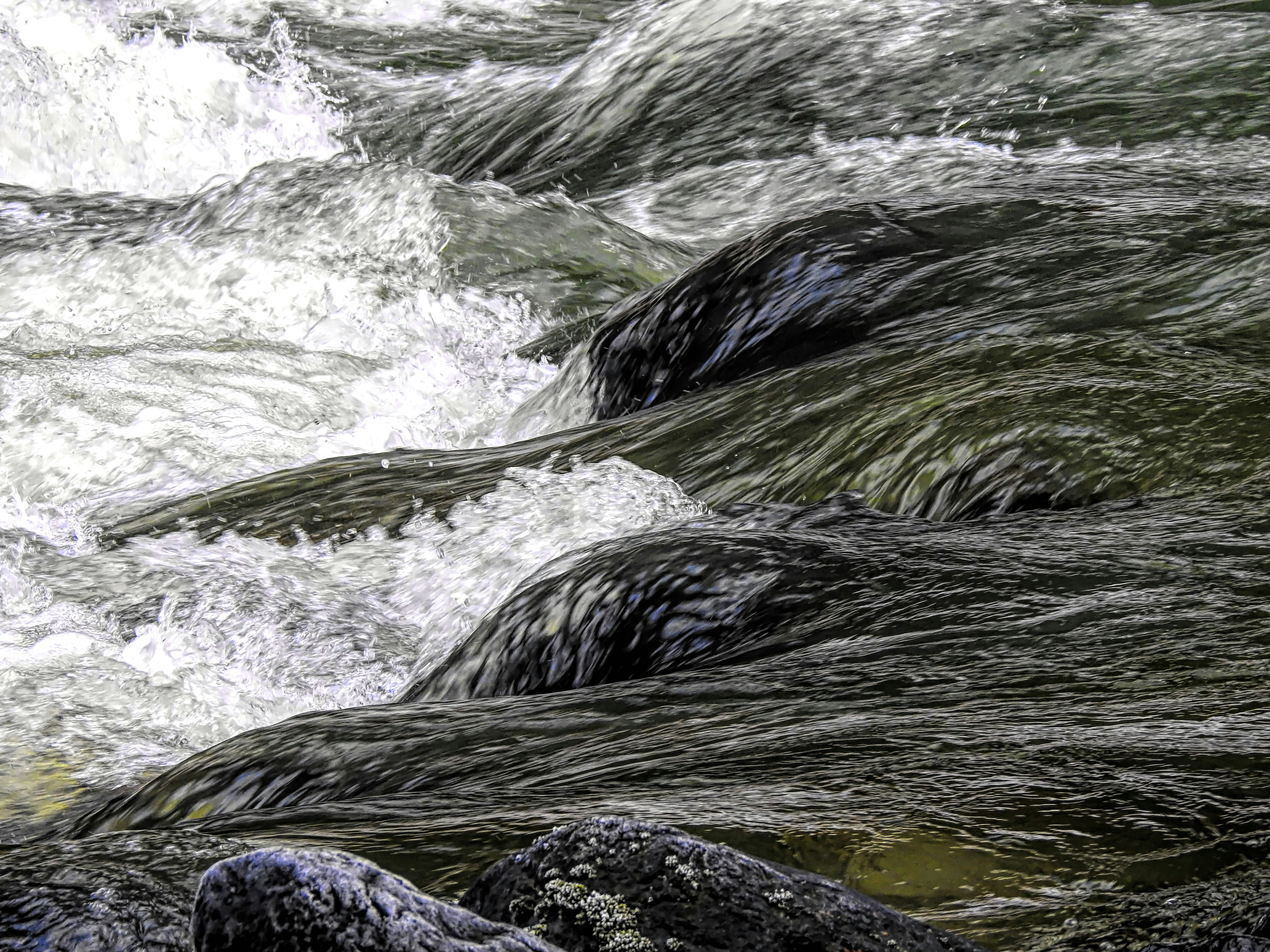 Fast flowing river water crashing over rocks, representing chronic stress overload and somatic stress management in Milborne St Andrew.